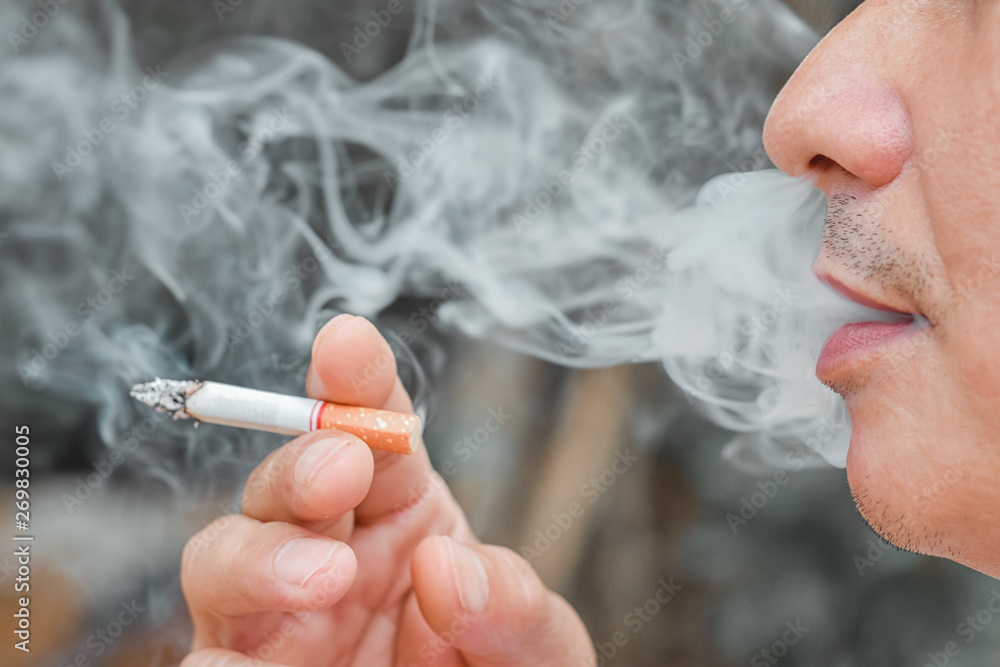 hydrogen cyanide in tobacco Man smoking cigarette with many smoke,when a cigarette is burning, they  create more chemicals. These nicotine, tar, and carbon monoxide,  formaldehyde, ammonia, hydrogen cyanide, arsenic and DDT Stock-foto
