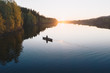 © Beatrice - Young man paddling a canoe boat towards horizon at sunset on a reflecting calm river with trees around in Europe