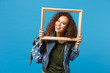 © ViDi Studio - Young african american girl teen student in denim clothes, backpack hold frame isolated on blue wall background studio portrait. Education in high school university college concept. Mock up copy space