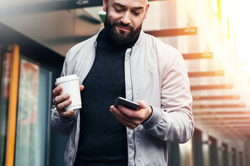 Portrait of young smiling man using smartphone on city street. Man sends text message. Lifestyle. Social networks.