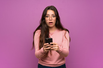 Wall Mural - teenager girl over purple wall surprised and sending a message