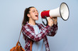 © luismolinero - Teenager student girl over isolated blue wall shouting through a megaphone