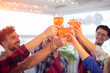 Group of young happy people toasting with glasses of spritz (cocktails) - rooftop birthday party with best friends concept