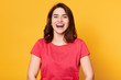 © sementsova321 - Close up portrait of beautiful cute dark haired girl in good mood wearing casual red tshirt, laughing, enjoying nice time indoors with friends, posing isolated against yellow studio background.