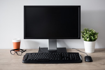 workplace with blank screen pc, flower pot, glasses and cup of coffee