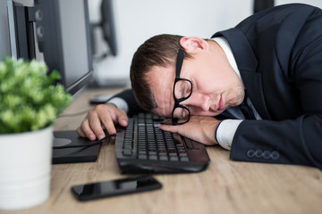 close up portrait of tired businessman sleeping on the table in modern office