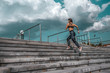 © byswat - Athlete girl runs jump sports jogging training summer city. Headphones telephone. Concept fitness fresh air, active lifestyle workout. Free space. Background steps clouds, morning evening motivation.
