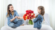 © puhimec - Mother's day. Little daughter with flowers congratulates her mother
