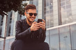 © Fxquadro - Smiling attractive man is chatting on mobile phone while sitting outside near building.