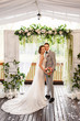 © Wedding photography - Wedding couple looking to camera near wedding arch after wedding ceremony. Portrait of happy newlyweds couple