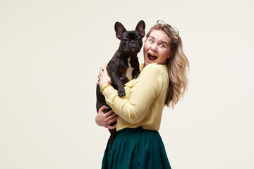 Wall Mural - Veterinary concept. Happy hipster woman playing with french bulldog on white background. Owner with funny dog resting, hugging and having fun. space for text