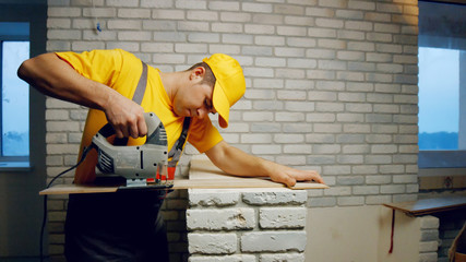 Builder cuts laminate. Builder cutting wood board with circular saw indoors. Repair, building and home improvement concept.