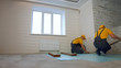 © DenisProduction.com - Male workers in uniforms installing floor boards. Repair of the apartment, laying laminate flooring.