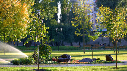 Beautiful summer park with landscape design. Irrigation system in city park. Beautiful sunny day.