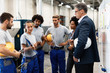 © Drazen - Female worker showing production reports to company managers in a factory.