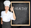 © Maridav - Healthy food menu at restaurant professional chef woman approving with ok hand sign satisfaction a balanced meal plan for diet weight loss. Text on black board sign for healthy lifestyle.