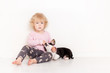 © yana136 - Portrait of a happy curly cute Caucasian little girl at home with a welsh corgi cardigan puppy playing on the floor in the room