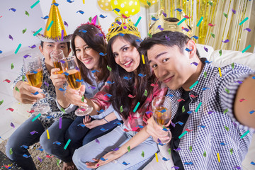 Happy young people take selfie at a birthday party