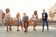 Group of diverse young people skateboarding and rolling in urban area
