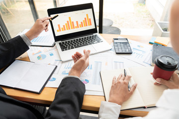 two young businessmen partner explaining information and pointing at report data discussing strategy