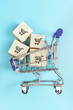 © Elena - Mini cart with boxes. The concept of on the Internet store and delivery of goods.