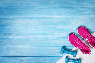 Fitness shoes over blue planks background. Sport shoes and accessories for sports activities on blue modern wooden floor, top view.