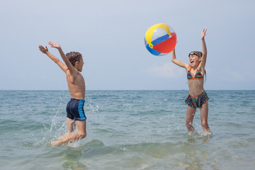 Two happy little children playing on the beach at the day time.