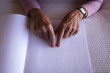 © Wavebreak Media - Blind active senior woman hands reading a braille book on bed in bedroom at home
