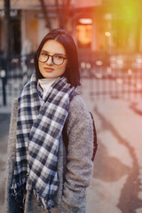 Wall Mural - Attractive young girl wearing glasses in a coat walking on a sunny day