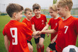 © matimix - Happy boys play team sport. Kids smiling in school sports team. Junior sports teamwork; kids put hands together. Cheerful children boys players of school soccer team. Happy boys in youth football team