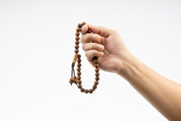 Wall Mural - Hand holding a muslim rosary beads or Tasbih on white background. Copy space and selective focus