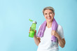 © Pixel-Shot - Sporty mature woman with towel and bottle of water on color background