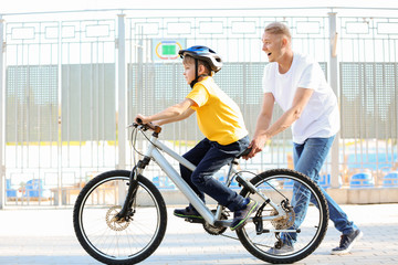 Poster - Father teaching his son to ride bicycle outdoors