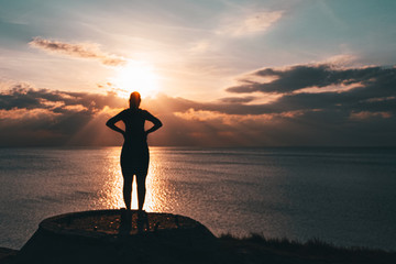 Wall Mural - silhouette of a young girl. standing and watching the sunset on the sea.