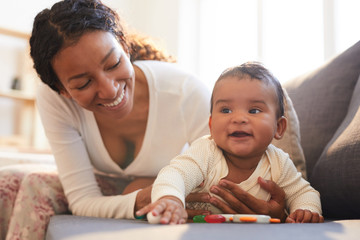 Wall Mural - Positive loving young black mother spending beautiful time with her baby on maternity leave at home