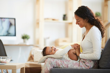 positive beautiful young african mother with curly hair expressing her love relation to laughing bab