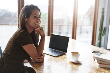 Good-looking successful ambitious female entrepreneur sit cafe co-working space turn aside smiling pleased laughing talking coworkers prepare project sit near laptop piles books drink coffee