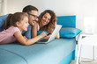 © BalanceFormCreative - Happy family lies on bed and watching something on laptop.Laughing and fun.