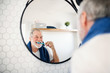 © Halfpoint - A senior man brushing teeth in bathroom indoors at home. Copy space.