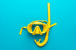 flat lay shot of yellow diving mask with snorkel over turquoise blue background. minimalist photo of dive mask and snorkel with central composition