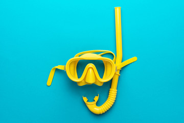 flat lay shot of yellow diving mask with snorkel over turquoise blue background. minimalist photo of dive mask and snorkel with central composition