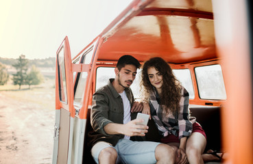 Wall Mural - Young couple on a roadtrip through countryside, taking selfie.