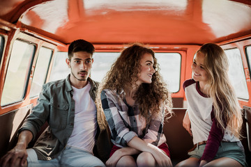 Wall Mural - A group of young friends on a roadtrip through countryside, sitting in a minivan.