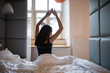 © F8  \ Suport Ukraine - Rear view of young happy woman woke up in the morning in the bedroom by the window