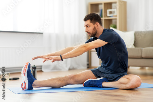 Cuadros en Lienzo sport, fitness and healthy lifestyle concept - man stretching leg on exercise ma