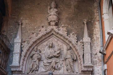 Stone sculpture of St Mary holding baby Jesus and two Apostles on her sides