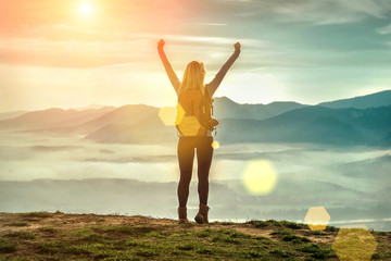 Happy woman tourist stay with open hands up on the green grass o