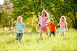 © Andrey - a group of children playing and running in the park on a green gozon.