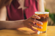 © Максим Галінский - beautiful girl holds a glass of cold coffee mixed with ice and orange juice on cafe background. Selective focus