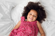 © Lisa Tichané - Smiling little girl with afro hair lying on bed
